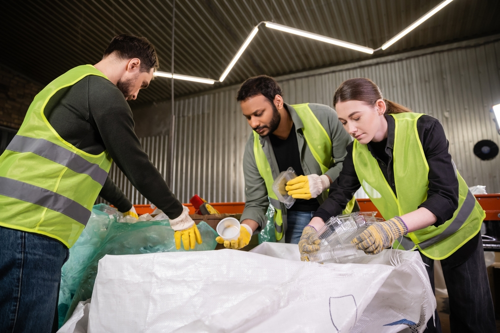 Young,Worker,In,Reflective,Vest,And,Gloves,Holding,Plastic,Containers